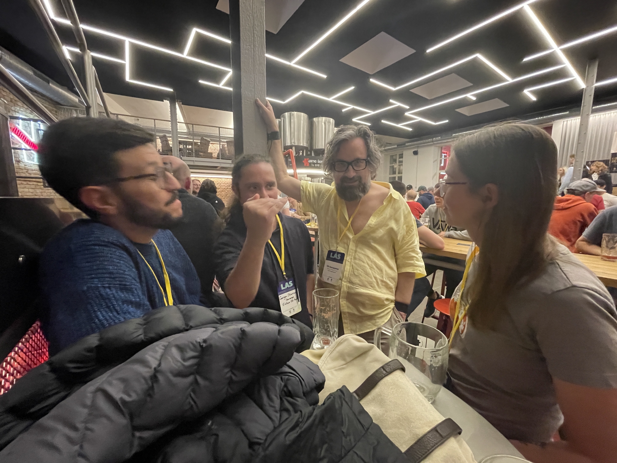 Photo of a group of folks having an engrossed conversation with me and others in Harrys Bar as the get-together really got underway